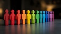 Colorful wooden figures arranged in rainbow spectrum from red to purple representing diversity, inclusion, teamwork and unity in business concepts.