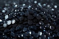 Dark glittering crystals with water droplets in macro photography, creating dramatic contrast between black minerals and sparkling light reflections on wet surface.