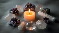 Healing crystals and gemstones arranged in circle around glowing candle for meditation, spiritual wellness, chakra balancing and holistic therapy practices.