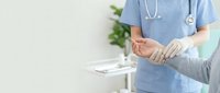 Healthcare professional in blue scrubs checking patient pulse during medical consultation in bright clinic with copy space.