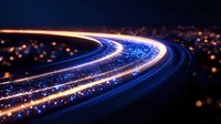Long exposure night photography of curved highway with blue and orange light trails from moving vehicles against dark cityscape with bokeh lights.