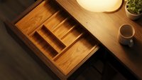 Wooden kitchen drawer organizer with compartments for cutlery and utensils in modern home interior with warm lighting and coffee cup on counter.