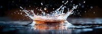Dynamic water splash creating crown-shaped droplet formation with golden reflections on dark surface for beverage advertising and liquid motion concepts.