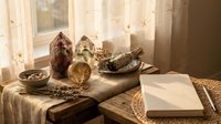 Spiritual healing crystals, sage bundles, and meditation tools arranged on rustic wooden table with warm natural lighting for wellness practices.