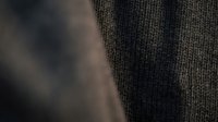 Close-up macro shot of brown knitted wool fabric texture with soft natural lighting showing detailed fiber weave pattern for textile and fashion design projects.