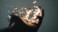 Outstretched hand holding magical glowing light particles against dark background, creating ethereal atmosphere for spiritual or fantasy concepts.