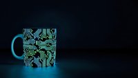 Coffee mug with electronic circuit board pattern glowing in blue light on dark background for tech enthusiasts and engineers.