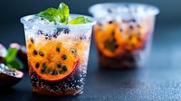 Refreshing cola beverage with ice cubes and mint leaves in clear glass, carbonated drink served cold for summer refreshment and entertaining.