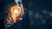 Businessman touching glowing security shield icon with lock symbol representing cybersecurity protection and data safety in digital business environment.
