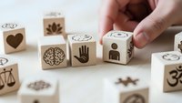Hand arranging wooden cubes with mindfulness symbols including brain, heart, meditation icons on neutral background for wellness concepts.