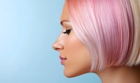 Side profile of young Asian woman with pink pastel bob haircut and closed eyes against blue background, showing modern beauty and hair coloring trends.