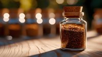 Small glass jar with cork lid containing brown coffee granules on wooden surface with warm bokeh lights in background.