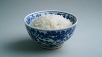 Cooked white rice in traditional blue and white porcelain bowl on neutral background for culinary and food photography projects.