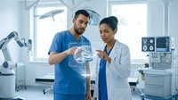 Two diverse medical professionals examining clear IV fluid bag in modern hospital operating room with surgical equipment and bright lighting.