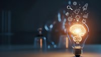 Glowing light bulb with innovation icons floating above representing creative ideas, business solutions, and technological advancement in modern workspace.