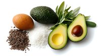 Fresh ripe avocado cut in half with pit, chia seeds, sea salt crystals and kumquat on white background, healthy superfood ingredients for nutritious eating.