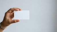 Close-up of a hand holding a blank white card against a neutral background, suitable for branding, business presentations, and marketing mockups.