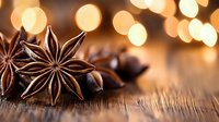Star anise pods on rustic wooden surface with warm golden bokeh lights in background creating cozy festive atmosphere for winter holiday season cooking and baking.
