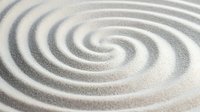 Mesmerizing spiral pattern in white and gray sand creates meditative zen garden effect, with concentric circles forming hypnotic swirl design on textured surface.