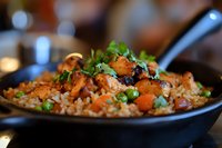 Flavorful Asian stir-fried chicken with brown rice, carrots, and fresh cilantro garnish served in black bowl, shallow depth of field food photography.