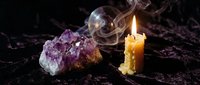 Mystical scene with burning candle, amethyst crystal and crystal ball creating magical atmosphere for spiritual practices and fortune telling rituals.