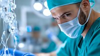 Middle Eastern male surgeon in scrubs and mask focused on medical procedure in operating room with blurred background and medical equipment.
