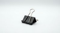 Black metal binder clip isolated on white background for office supplies and document organization needs.