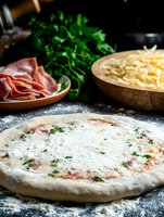 Raw pizza dough with tomato sauce and cheese on dark background, fresh ingredients like prosciutto, grated mozzarella and parsley for homemade Italian cooking.