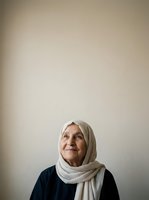 Senior woman wearing white headscarf and dark clothing, looking upward with contemplative expression against neutral background. Suitable for healthcare, wellness, spirituality, diversity, aging, and portrait projects.