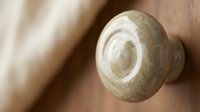 Wooden cabinet knob with natural grain texture on blurred wood surface background for furniture hardware and home renovation projects.
