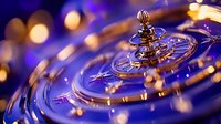 Futuristic circular metallic rings with golden and purple light effects creating dynamic spiral motion pattern against dark background. Suitable for tech concepts.