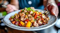 Colorful stir-fried chicken with bell peppers, carrots and fresh herbs served on rustic ceramic plate, close up view of homestyle Asian cuisine.