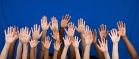 Diverse group of raised hands against blue background showing unity, volunteering, participation and community engagement in teamwork concept.