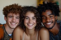 Diverse group of young smiling friends with different skin tones and curly hairstyles posing together in casual setting, showing genuine joy and connection.