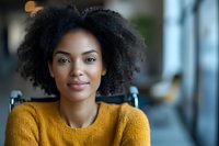 Young African American woman with natural curly hair wearing yellow sweater smiling at camera, expressing confidence and joy in modern office setting.