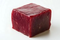 Fresh raw beef cube with deep red color and marbled texture on white background, isolated macro shot showing meat quality and natural grain structure.