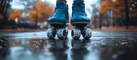 Vintage blue roller skates standing on wet asphalt during autumn rain, with orange fall foliage bokeh background creating nostalgic retro mood.