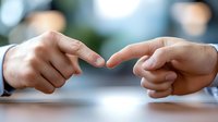 Two hands reaching toward each other with fingers almost touching, symbolizing connection, partnership, and human interaction in professional setting.