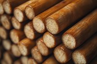 Stacked wooden logs in warm brown tones showing natural wood grain texture and circular cut ends, arranged in parallel rows creating depth and pattern.