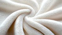 Soft white fleece fabric with twisted spiral folds creating dynamic texture and shadows, close-up view showing plush material surface detail for textile and design backgrounds.