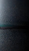 Dark textured surface with fine grain pattern and subtle light reflection creating depth and contrast for modern design backgrounds.
