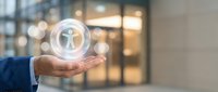 Person icon glowing in transparent sphere held by businessman hand in office environment with blurred background for business concepts.