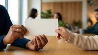 Diverse male and female professionals exchanging blank business card at wooden table during corporate meeting, suitable for business communication and networking concepts.