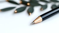 Sharp graphite pencil tip in macro view with soft focus floral decoration elements in background, minimalist composition for creative and educational concepts.