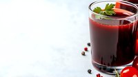 Fresh tomato juice garnished with parsley leaf in glass on white background with cherry tomatoes and black peppercorns, healthy vegetable drink.