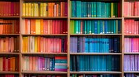 Colorful library bookshelves with books arranged by color creating rainbow spectrum effect, perfect for education, knowledge organization, and interior design concepts in modern spaces.
