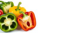 Fresh colorful bell peppers sliced in half showing seeds and interior on white background isolated for healthy cooking and nutrition concepts.