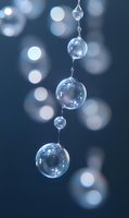 Crystal clear water drops suspended in chain formation against dark blue background with soft bokeh lights, showcasing natural refraction and purity in macro photography.