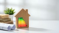 Wooden house model with energy efficiency rating scale from A to G for eco-friendly home construction and sustainable building concepts.