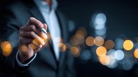Businessman holding pen against blurred city lights at night, representing corporate leadership and strategic decision-making in urban business environment.